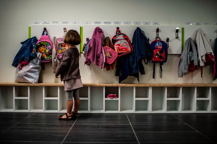 little girl putting backpack away at her cubby, preschool