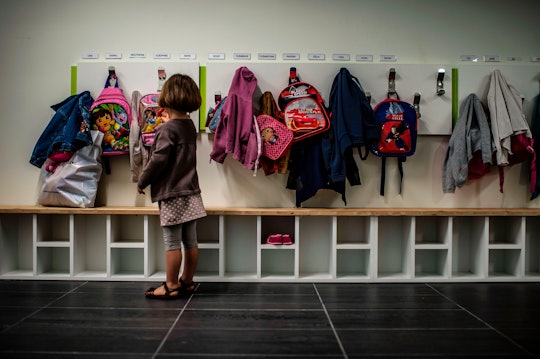 little girl putting backpack away at her cubby, preschool