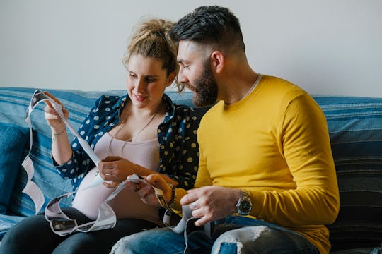 young couple looking at ultrasound pictures, pregnant mom