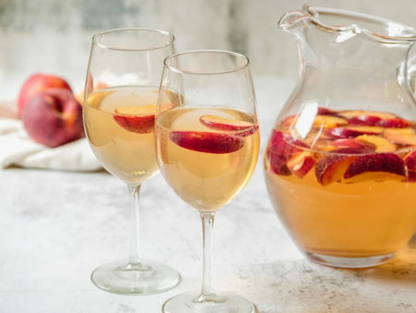 Two glasses and a pitcher full of peach sangria.