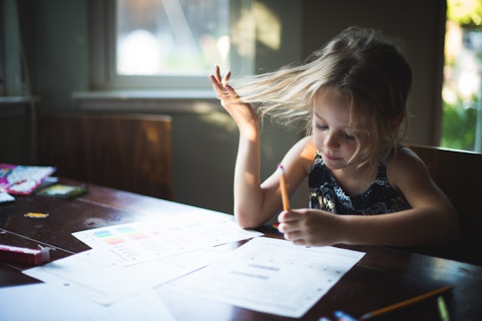 A girl plays with her hair while doing homework