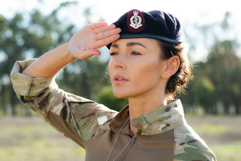 Michelle Keegan as Sgt Georgie Lane wearing army fatigues and a beret with her arm raised in a salut...