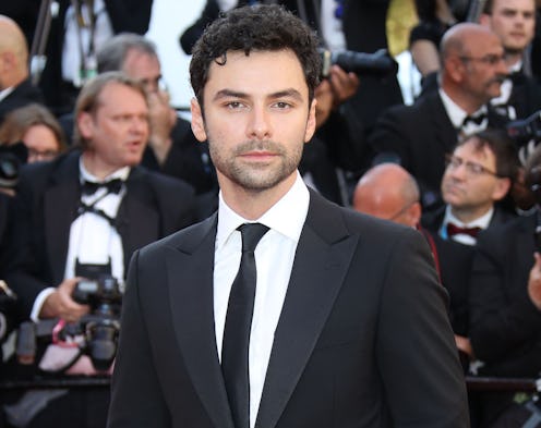 Aidan Turner wearing a suit at a premier with paparazzi in the background