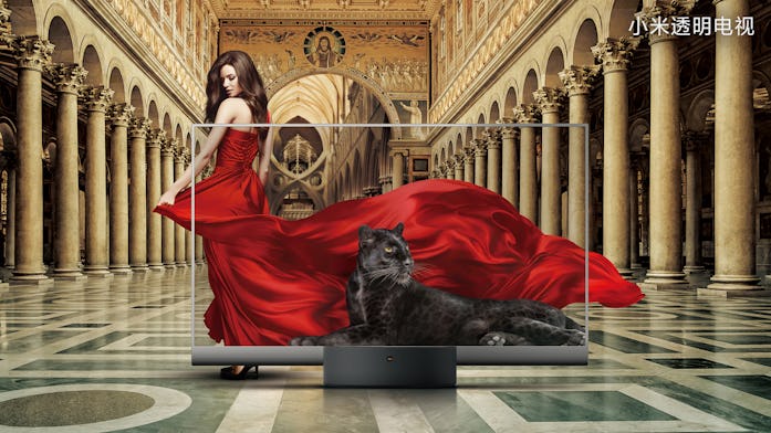 A see-through TV set by Xiaomi can be seen showing a black panther in reclining position. A model is...