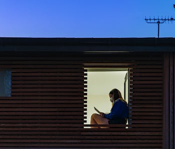 Teenage girl sitting in her window at home.