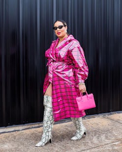 A plus-size model wearing a striped pink and black coat, snake skin boots and a pink handbag