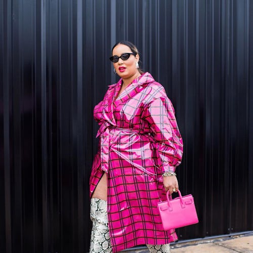 A plus-size model wearing a striped pink and black coat, snake skin boots and a pink handbag