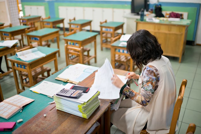 Teacher Grading Paperwork In empty classroom