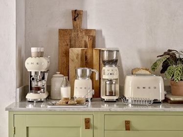 A set of cream SMEG appliances sit on a counter with breakfast food and ingredients.
