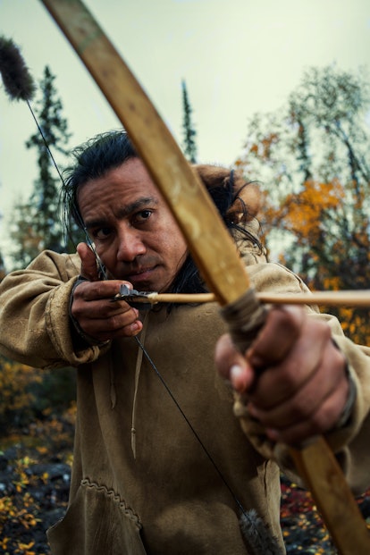 Amós Rodriguez pulls a bow and arrow taut, ready to fire.