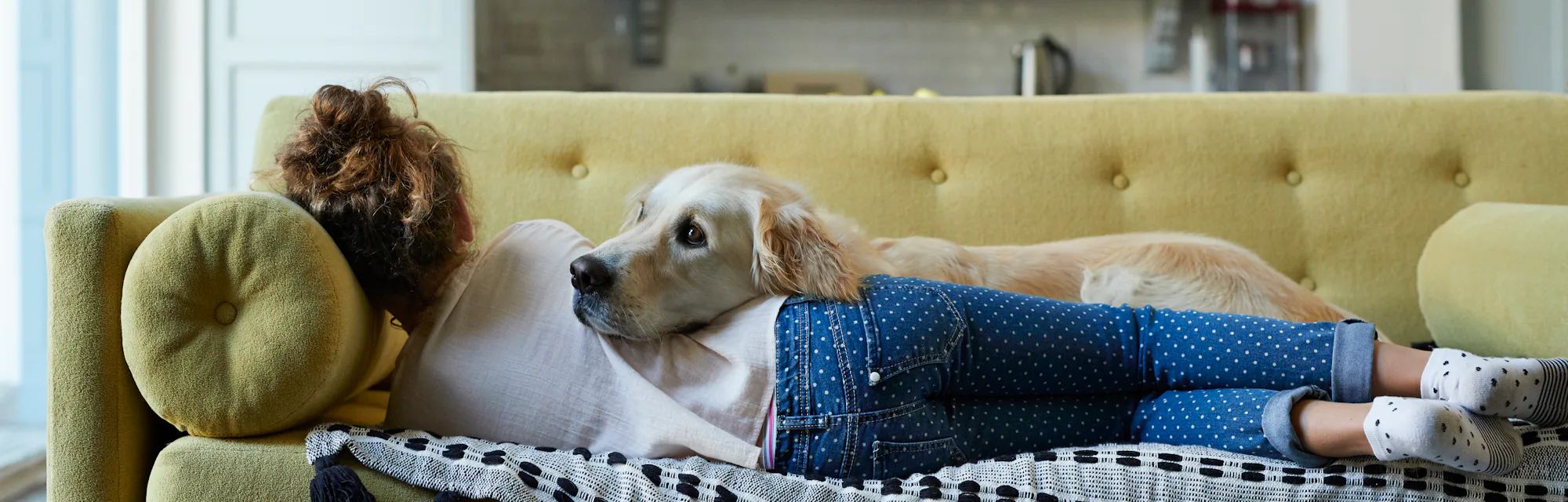 Woman laying on the couch with her Golden Retriever.
