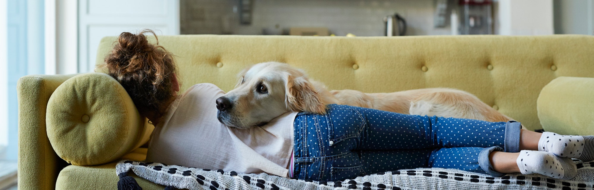 Woman laying on the couch with her Golden Retriever. 