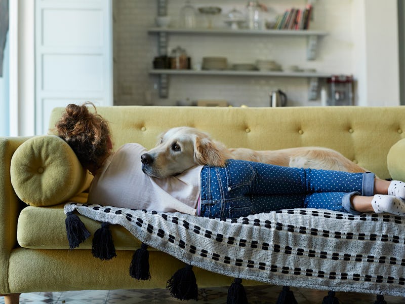 Woman laying on the couch with her Golden Retriever. 