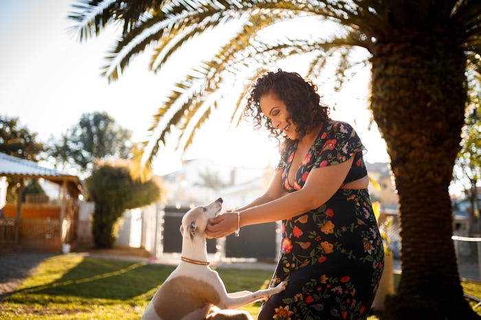 pregnant woman playing in yard with her dog