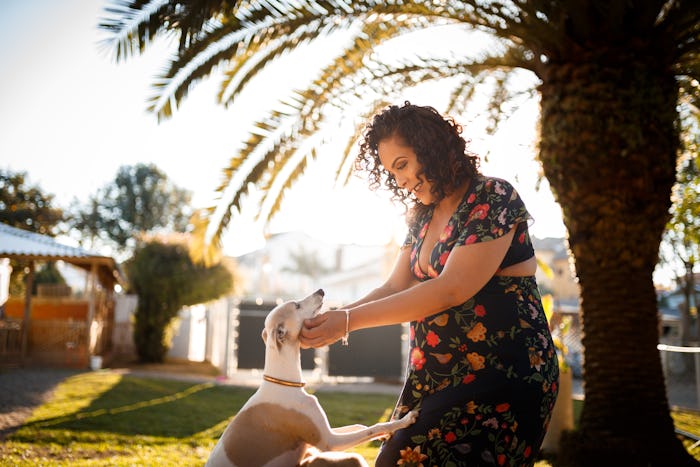 pregnant woman playing in yard with her dog