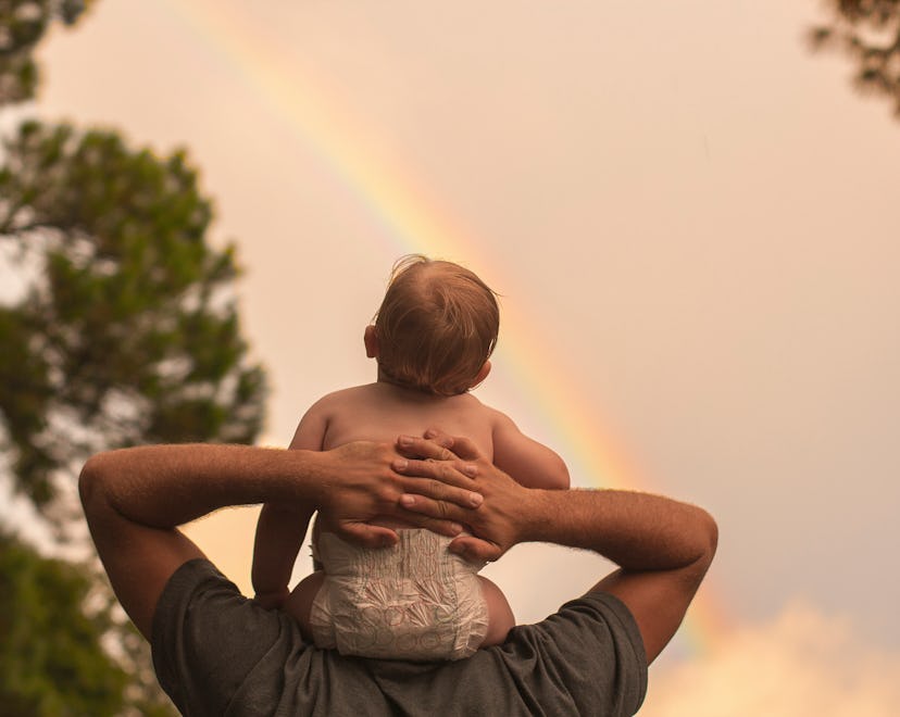 baby sitting on parent's shoulders watching rainbow in article about when is rainbow baby day
