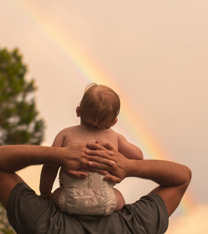 baby sitting on parent's shoulders watching rainbow in article about when is rainbow baby day