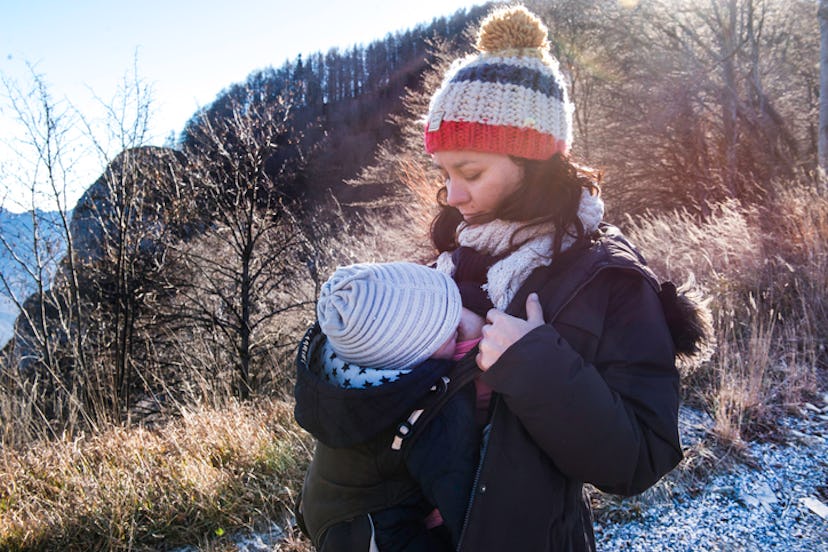 Mom breastfeeding baby in a baby carrier when it's cold outside