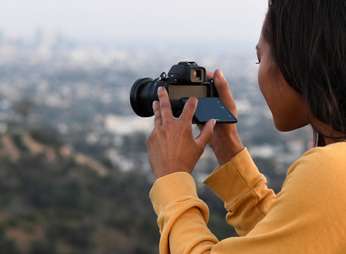 A Black woman using a Nikon Z 50 camera