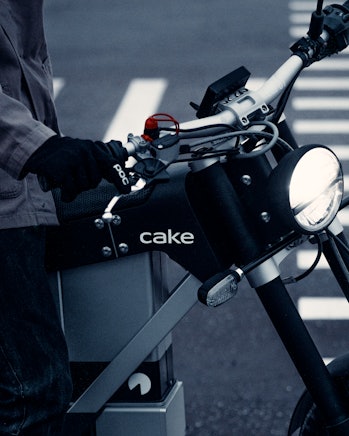 A close-up of the handlebars and front fork of a Cake Ink SL electric motorcycle