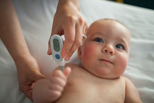 mother taking baby's armpit temperature before coronavirus test