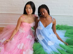 Two women sit on the floor, while wearing dresses from the Disney Princess x Lirika Matoshi collecti...