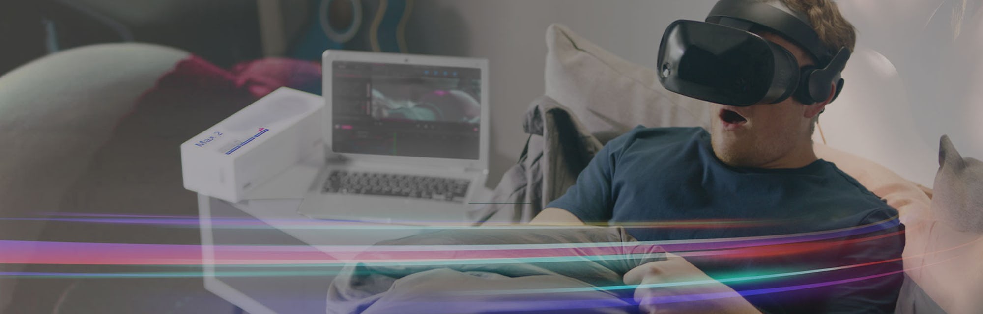 A man wearing a VR headset in bed reaching beneath his covers.