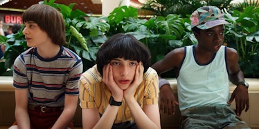 Will, Mike, and Lucas from Netflix's 'Stranger Things' sit on a bench at the Starcourt Mall and wait...