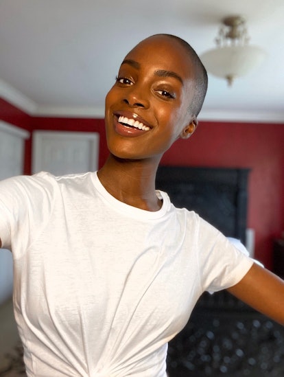 Madisin Rian posing in a white shirt in her living room with a huge smile on her face