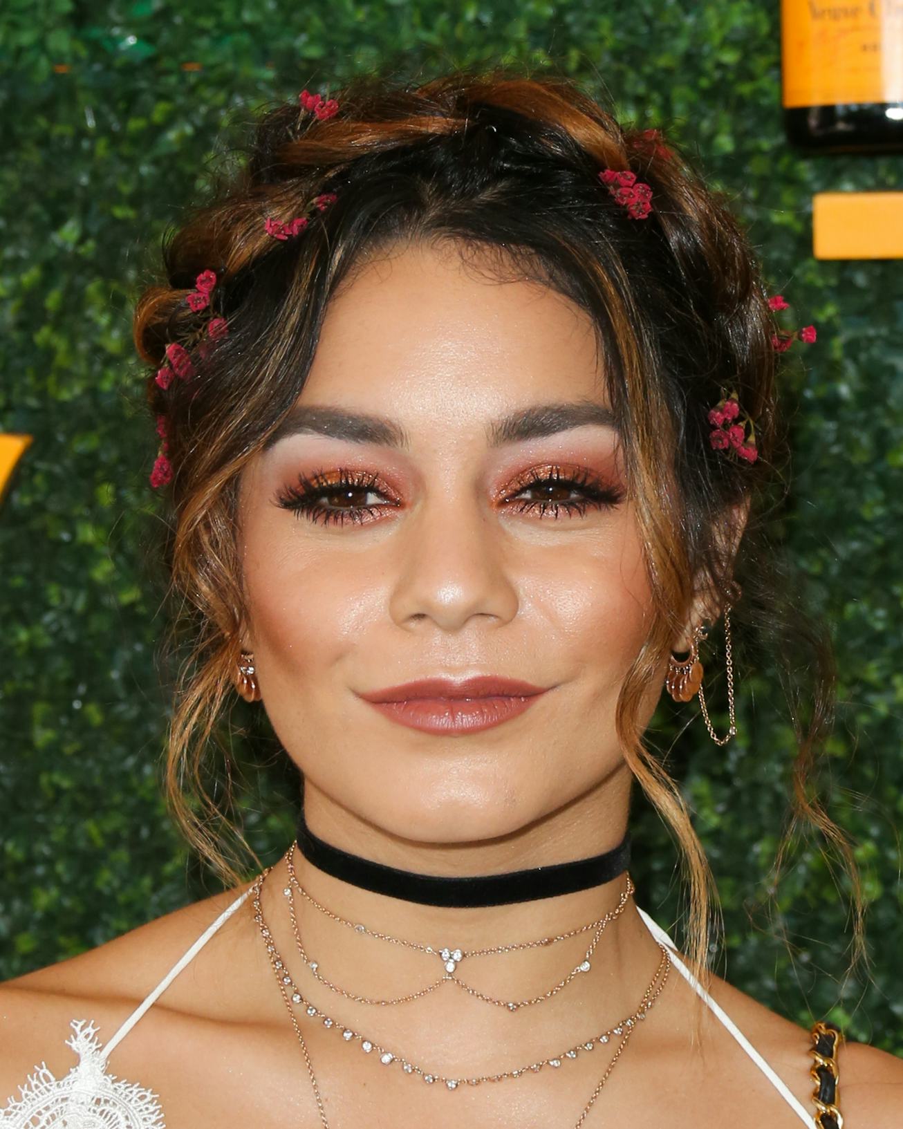 Actress Vanessa Hudgens wearing a black choker, necklace and flowers in her hair 