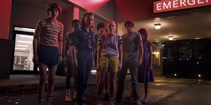 The cast of 'Stranger Things' stands outside of the Starcourt Mall in a spooky scene.