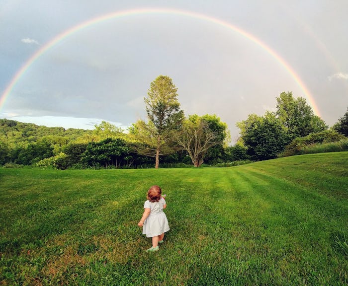 photo of baby on lawn staring at rainbow 