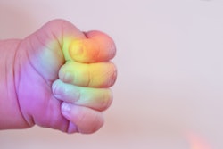 Rainbow baby's fist with rainbow reflecting on fingers