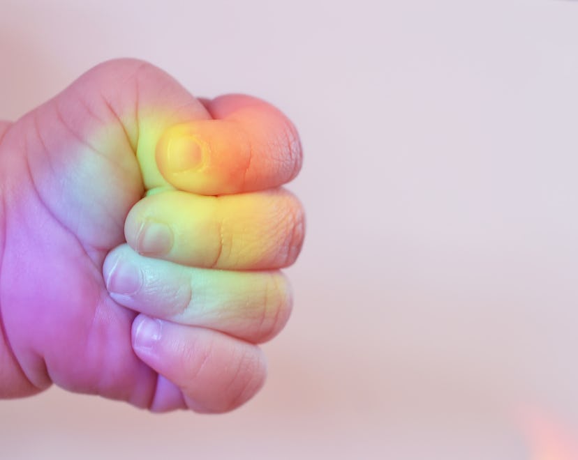 Rainbow baby's fist with rainbow reflecting on fingers in article about what is a rainbow baby and r...