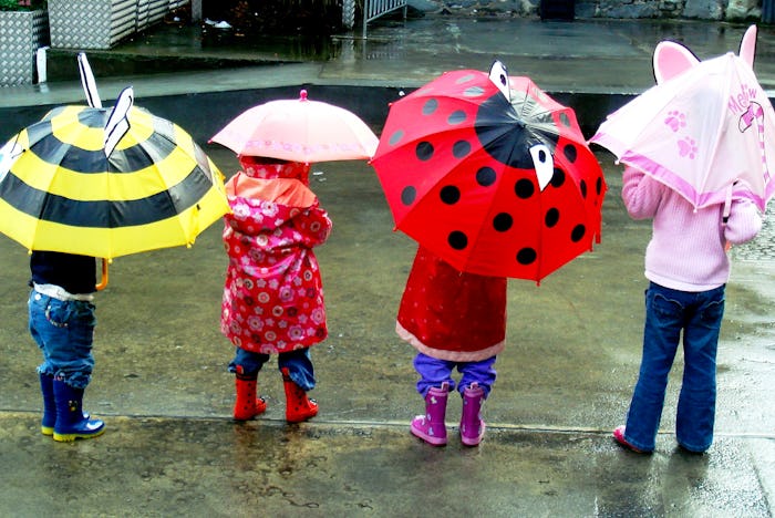 children standing in the rain with colorful umbrellas