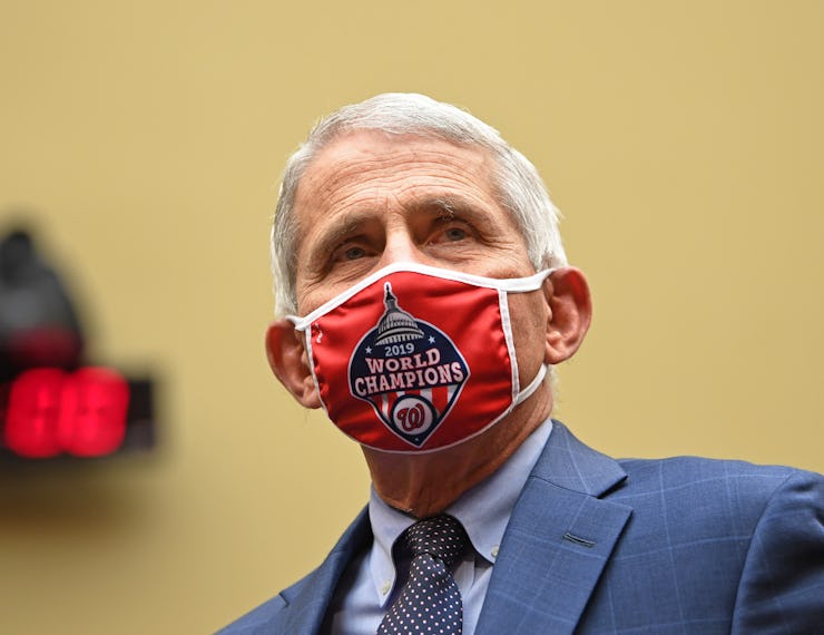 Anthony Fauci wearing a red Covid-19 mask with "2019 World Champions" sign