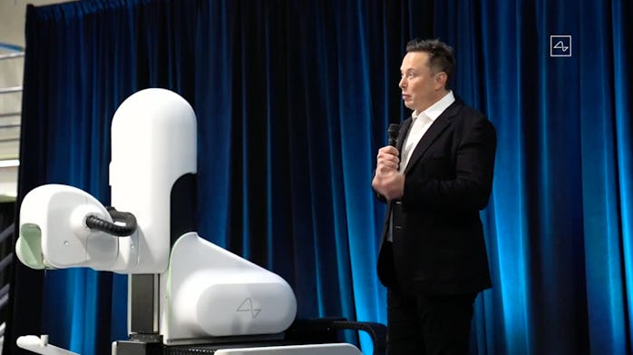 A Neuralink robot surgeon and Elon Musk on stage