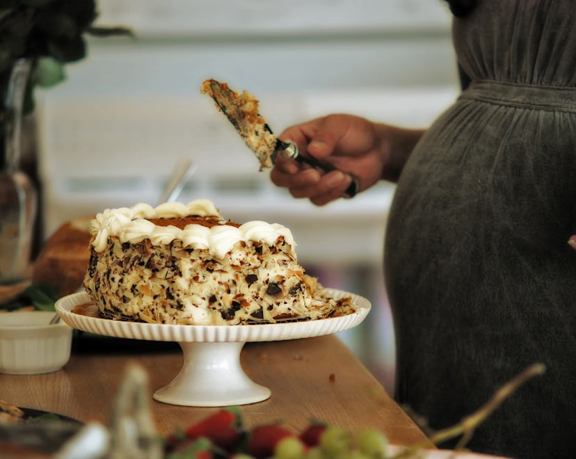 pregnant woman cutting baby shower cake