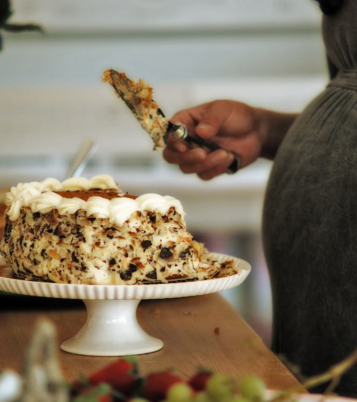 pregnant woman cutting baby shower cake