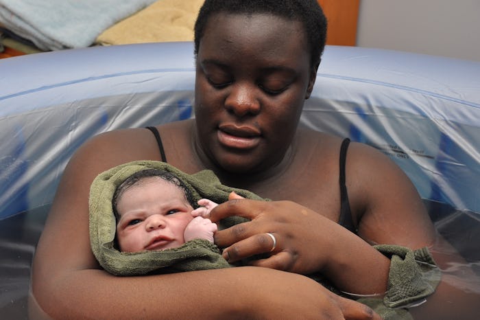 mom cradling newborn baby in tub after water birth