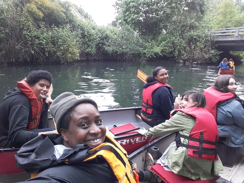Mercy Shammah taking a selfie with a group of people while kayaking outdoors