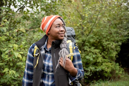 Mercy Shammah in a blue and white checked shirt and backpack in the outdoors