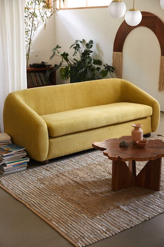 The Yoji Sofa from Urban Outfitters sits in a natural-themed space with a wood coffee table, rough r...