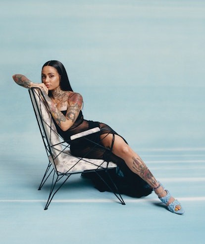Kehlani in a black Chanel dress that expresses her shoulders, leg and arm tattoos