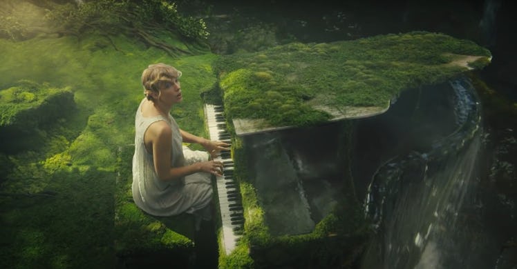Taylor Swift sits at a moss-covered piano in a jungle with a waterfall in her "cardigan" music video...