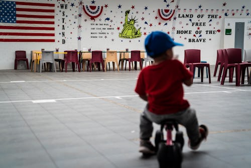 DILLEY, TX - AUGUST 23 : An immigrant child plays in front of patriotic phrases and symbols covering...