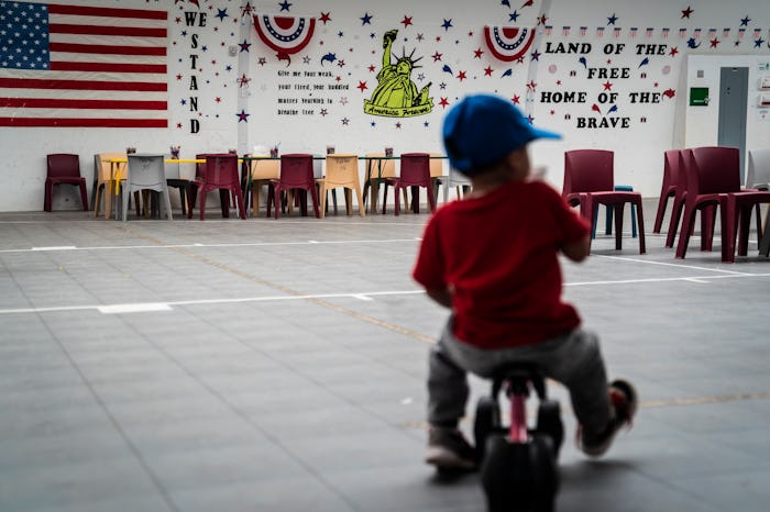 DILLEY, TX - AUGUST 23 : An immigrant child plays in front of patriotic phrases and symbols covering...