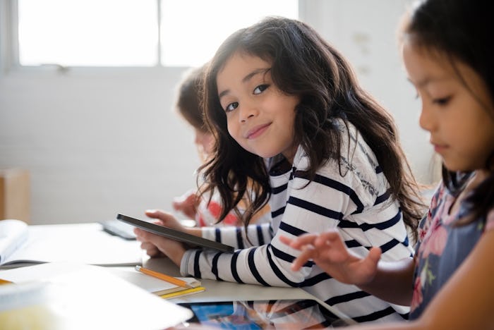 Girl smiling at desk next to peers