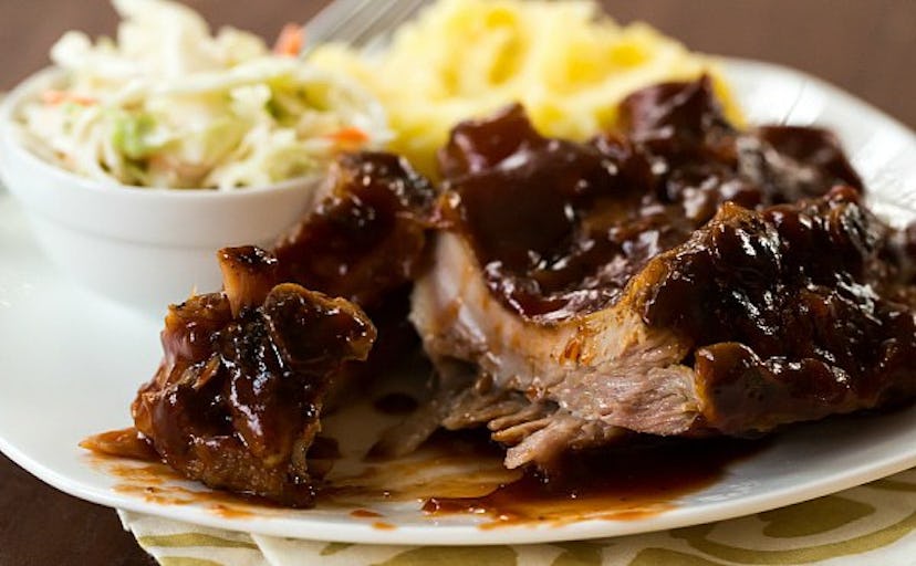 BBQ ribs on a white plate with coleslaw and another side dish