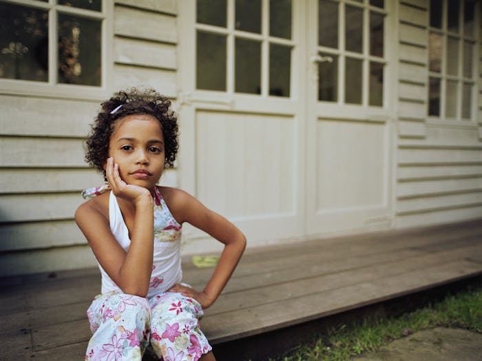 A young girl sits on a porch